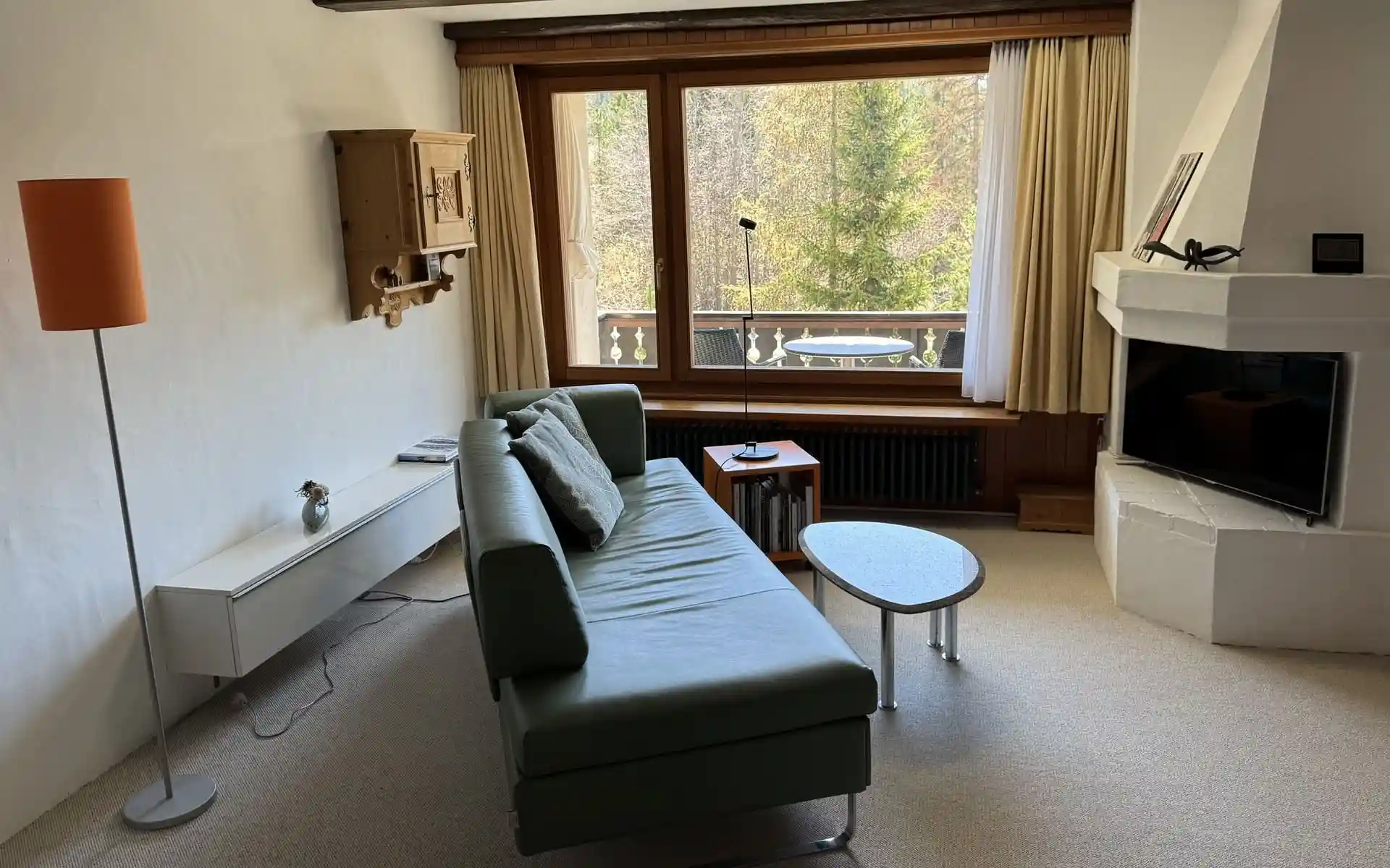 Wohnzimmer mit Sofa und Blick nach draussen in der Ferienwohnung Belvair 29 in La Punt Chamues ch im Engadin Graubünden